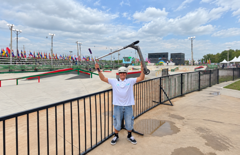 Mateo Correa posa feliz con su monopatín en alto frente al circuito de Street en Asunción.
